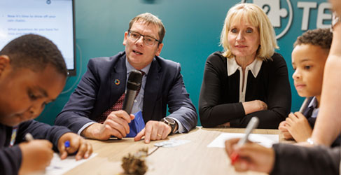Adults and children sitting at a table with pens and paper