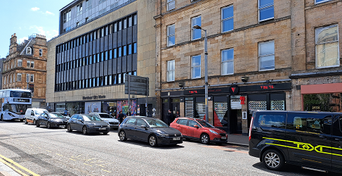 This image shows parked vehicles and a line of traffic on London Road in Glasgow