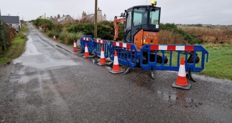 A mini-digger at the roadside, ready for work to begin to install a replacement water main to serve customers in Bayble, Isle of Lewis