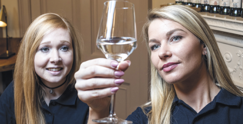 Two women holding up glass of water