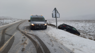 Scottish Water van parked beside crashed black car in snowy conditions.