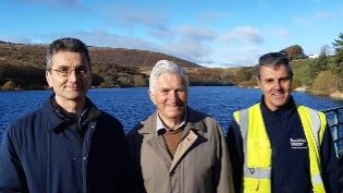 Picture of father, son, and Scottish Water Operative with reservoir in background