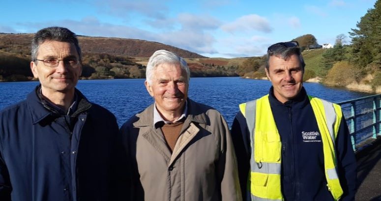 Picture of father, son, and Scottish Water Operative with reservoir in background