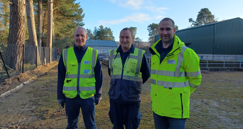 Three men in hi-vis jackets stand outdoors in a yard at Ballater Water Treatment Works