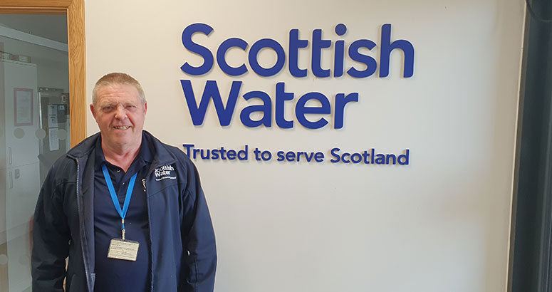 Man standing against a logoed wall