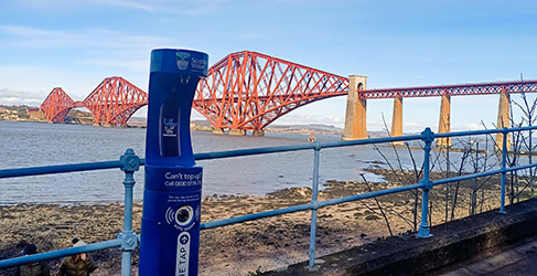 Blue water refill tap with Forth Raid Bridge in background