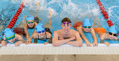 man and children in swimming pool