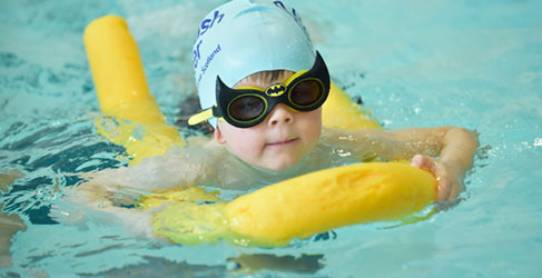child swimming with cap and goggles on