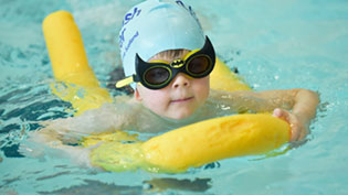 Child swimming with cap and goggles on