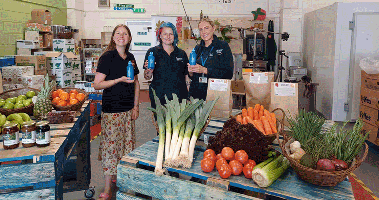 People standing holding water bottles in front of table of food 