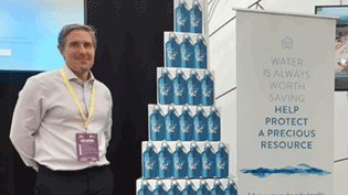 Man standing beside carboard pyramid of bottles