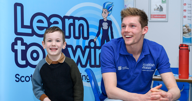 man and boy in front of Learn to Swim Signage