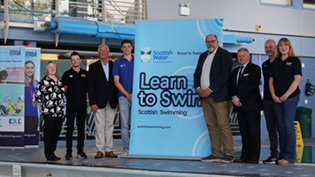 People posing around large Learn to Swim banners