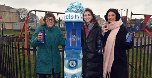 3 women standing with water bottles at a top up tap