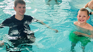 shows swimmer Nathan McKechnie in the pool with youngster Jack at Learn to Swim lesson
