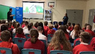 CWA presenting to Alehousewells School  CWA employees stand in front of projector screen presenting to rows of pupils