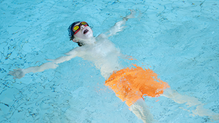 Learn to Swim School Swimming Safety Lesson Boy practicing float technique in pool