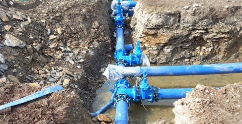 Image of bright blue water main being installed in the ground