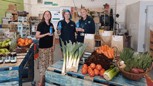 People standing holding water bottles in front of table of food 