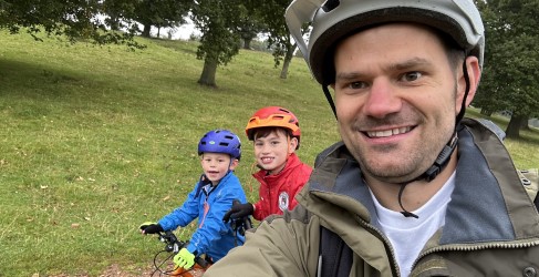 Three smiling people posing with cycling clothing on